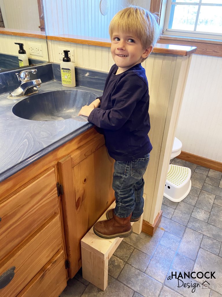 little boy standing on bathroom stool